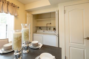 A kitchen with a table set for two and a window with curtains.